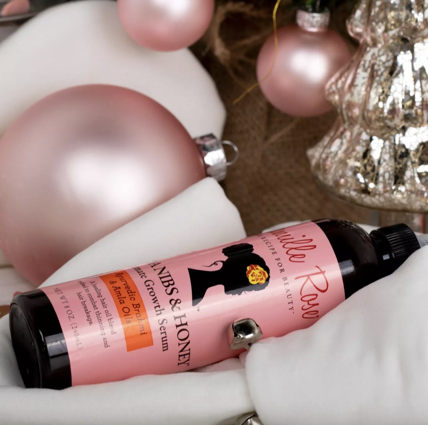 A bottle of hair growth oil and pink and white ornaments