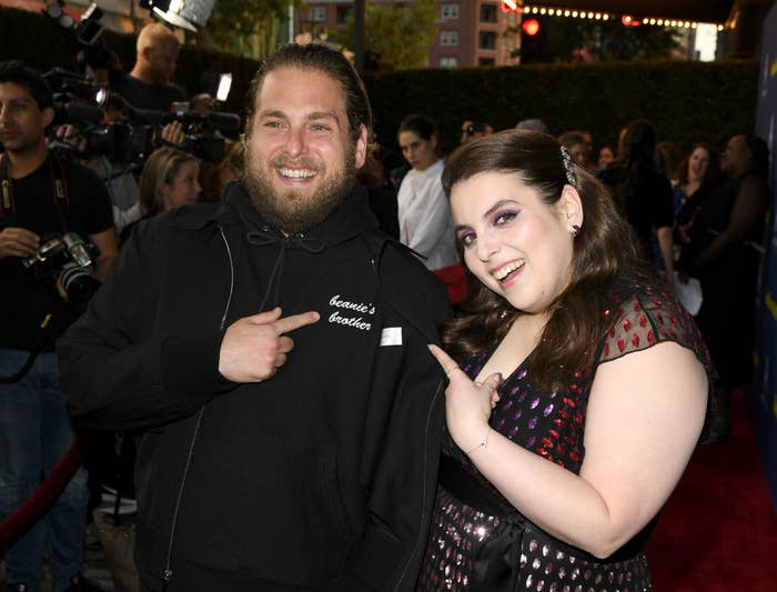 Beanie with Jonah on the red carpet. She wears a short-sleeved black and red dress and he wears a hoodie that reads &quot;beanie&#x27;s brother&quot; on the lapel
