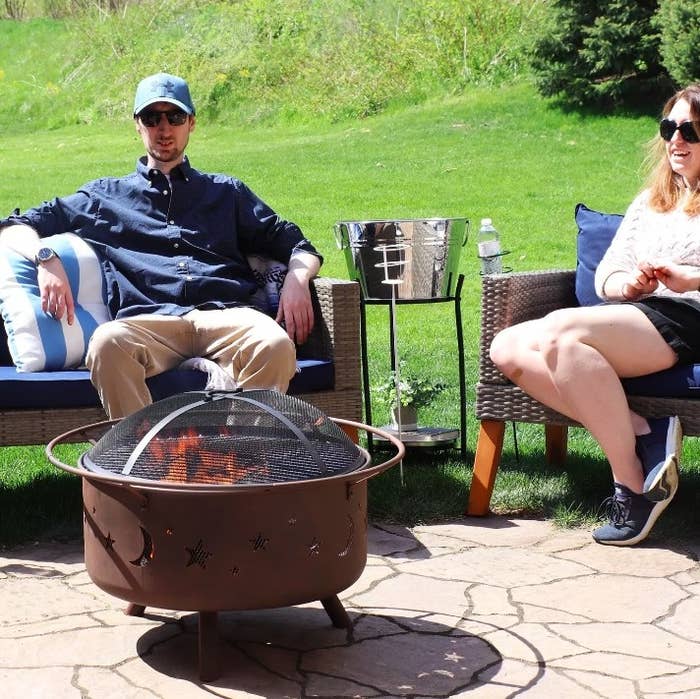 Two people enjoying a bonfire outside with the fire pit