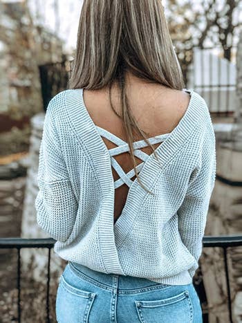 back view of a model wearing the sweater in light grey