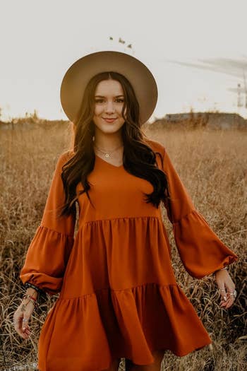 a reviewer wearing the long sleeve dress in orange