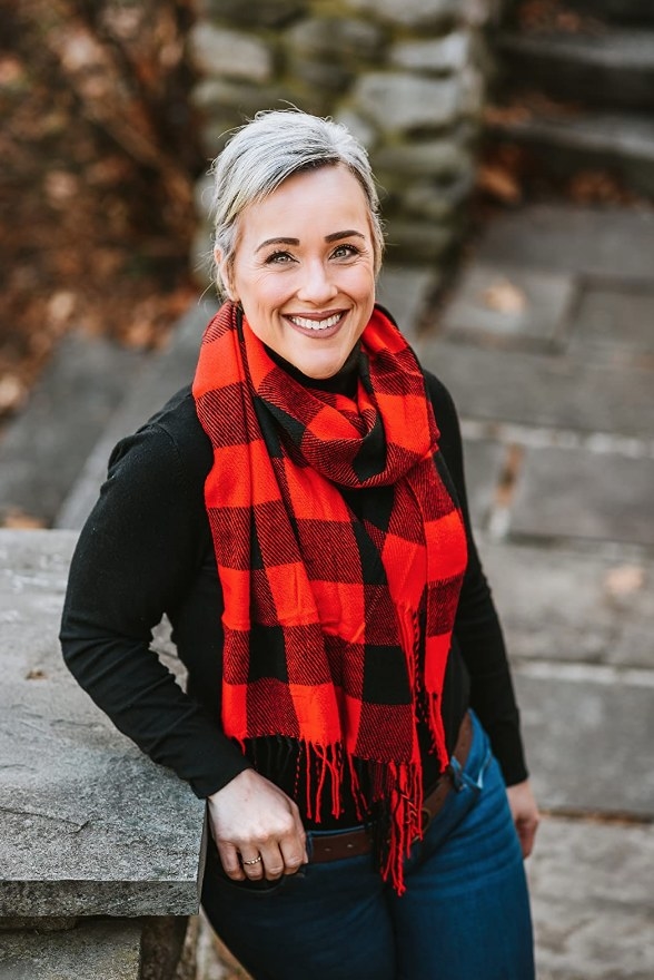 A reviewer wearing a black/red plaid scarf with tassels