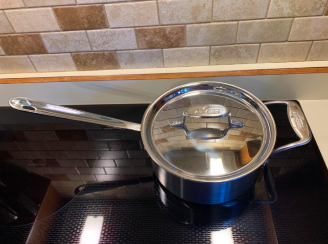 a reviewer&#x27;s photo of the stainless steel pan on an induction cooktop