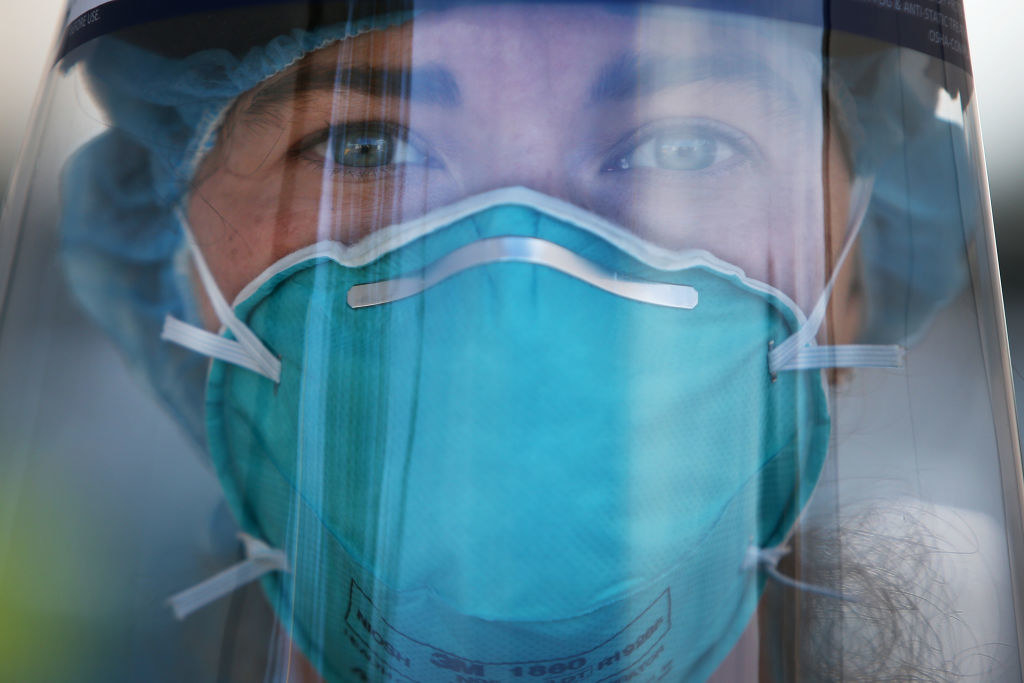 A closeup of a nurse wearing PPE and a face shield