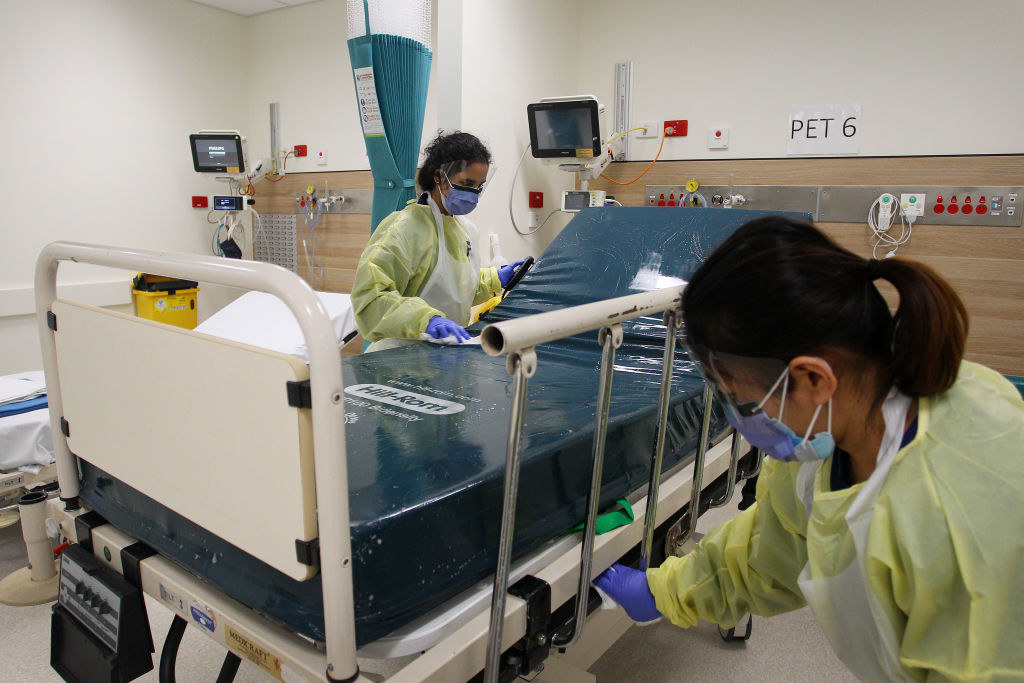 Two nurses dressed in PPE cleaning a bed in the COVID-19 ward
