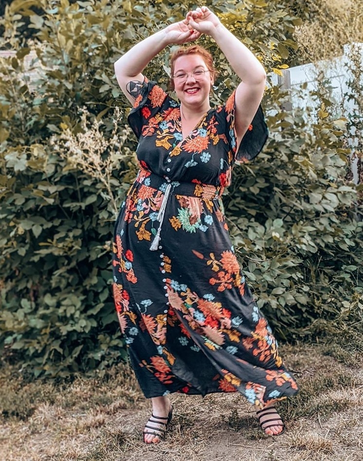 A reviewer wearing a black floral, boho-inspired, short-sleeved maxi dress