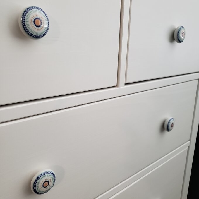 Reviewer&#x27;s picture of the blue, white, and gold knobs on a dresser
