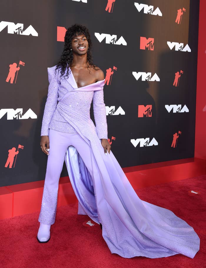 Lil Nas X on the red carpet in a suit-dress hybrid outfit and a shoulder-length wig