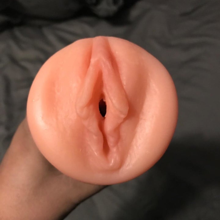 Model holding masturbator to display realistic opening