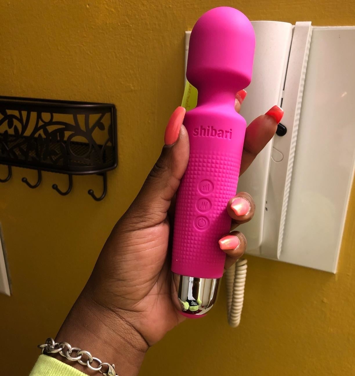 reviewer holding pink wand vibrator