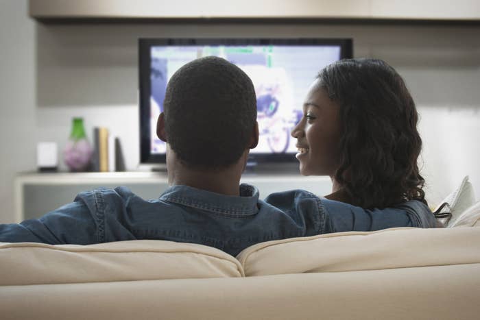A woman looks at her partner lovingly, while he continues watching TV