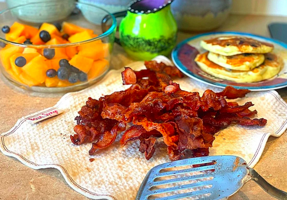 The bacon sponge covered in bacon on a kitchen counter