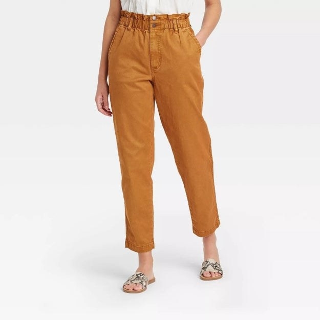 Model wearing mustard yellow pants with two pockets, stops at ankle