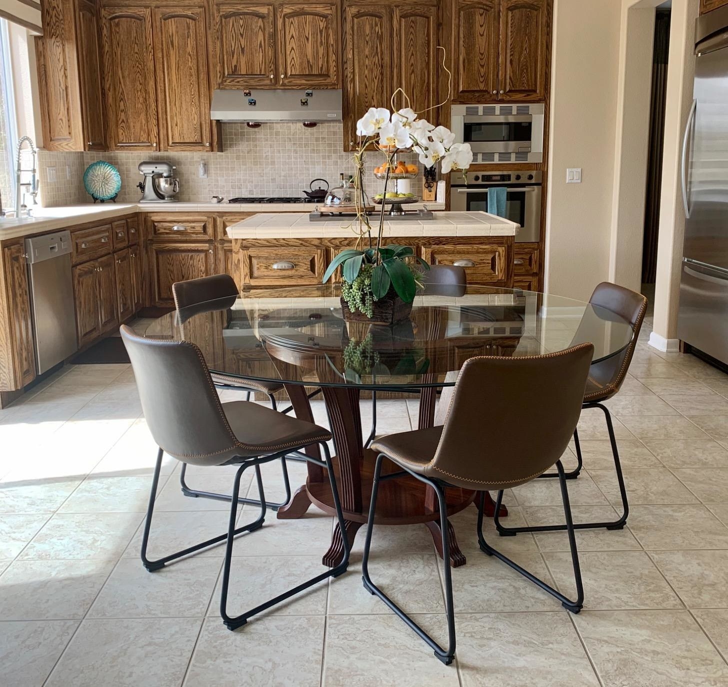 Reviewer&#x27;s dining chairs are around a circular glass dining table in the kitchen