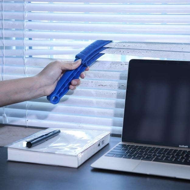 The blue cleaner removing dust from two blinds, top and bottom