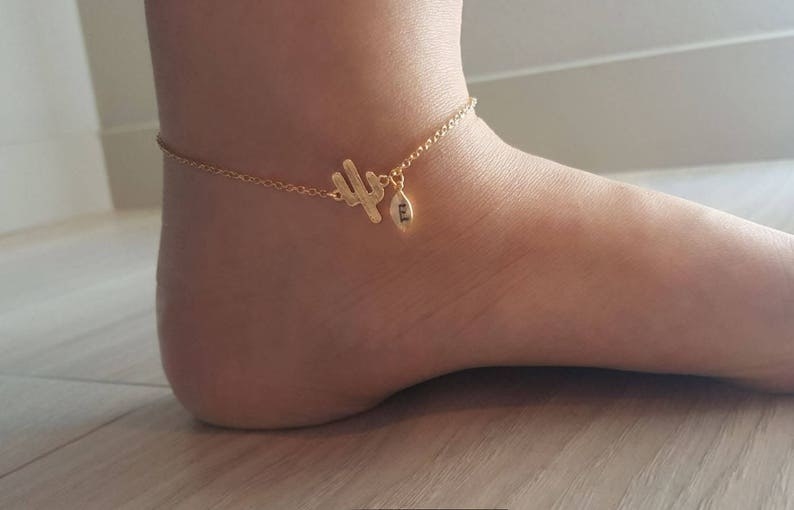 model wearing delicate gold anklet with cactus and initial charms