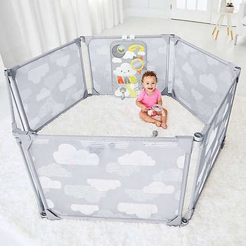 a gray netted play pen with clouds on it and a cloud-themed toy inside