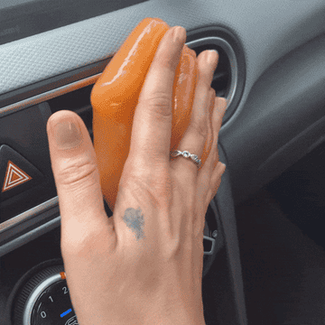 The writer rolling an orange putty over a car AC vent