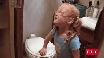 A little girl smelling a toilet