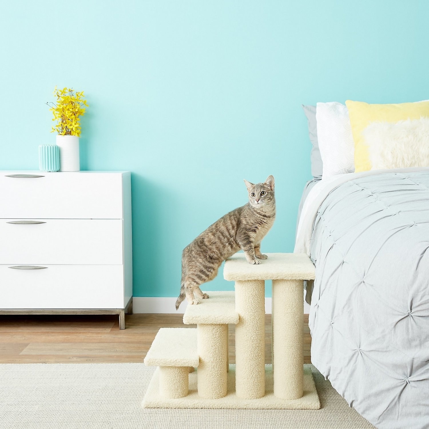 a striped cat climbing up the off-white stairs