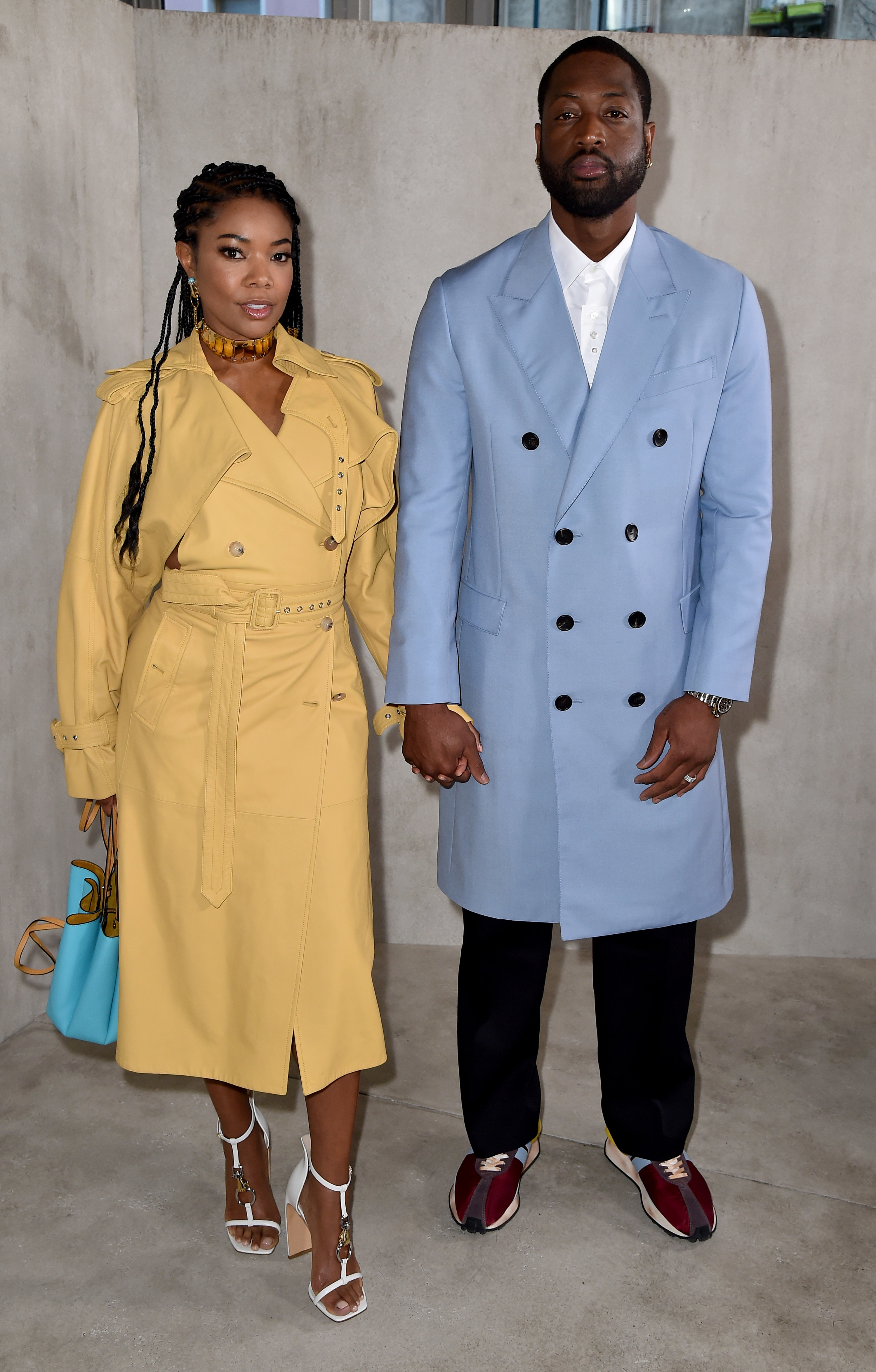 Gabrielle and Dwyane hand-in-hand wearing raincoats