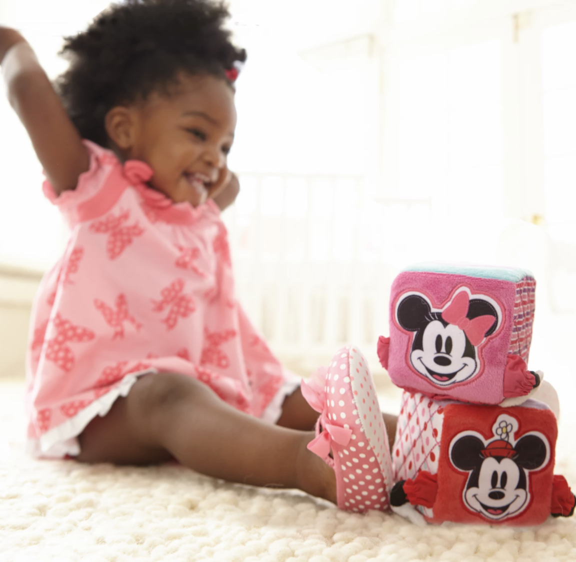 a baby playing with the soft blocks with minnie mouse on them