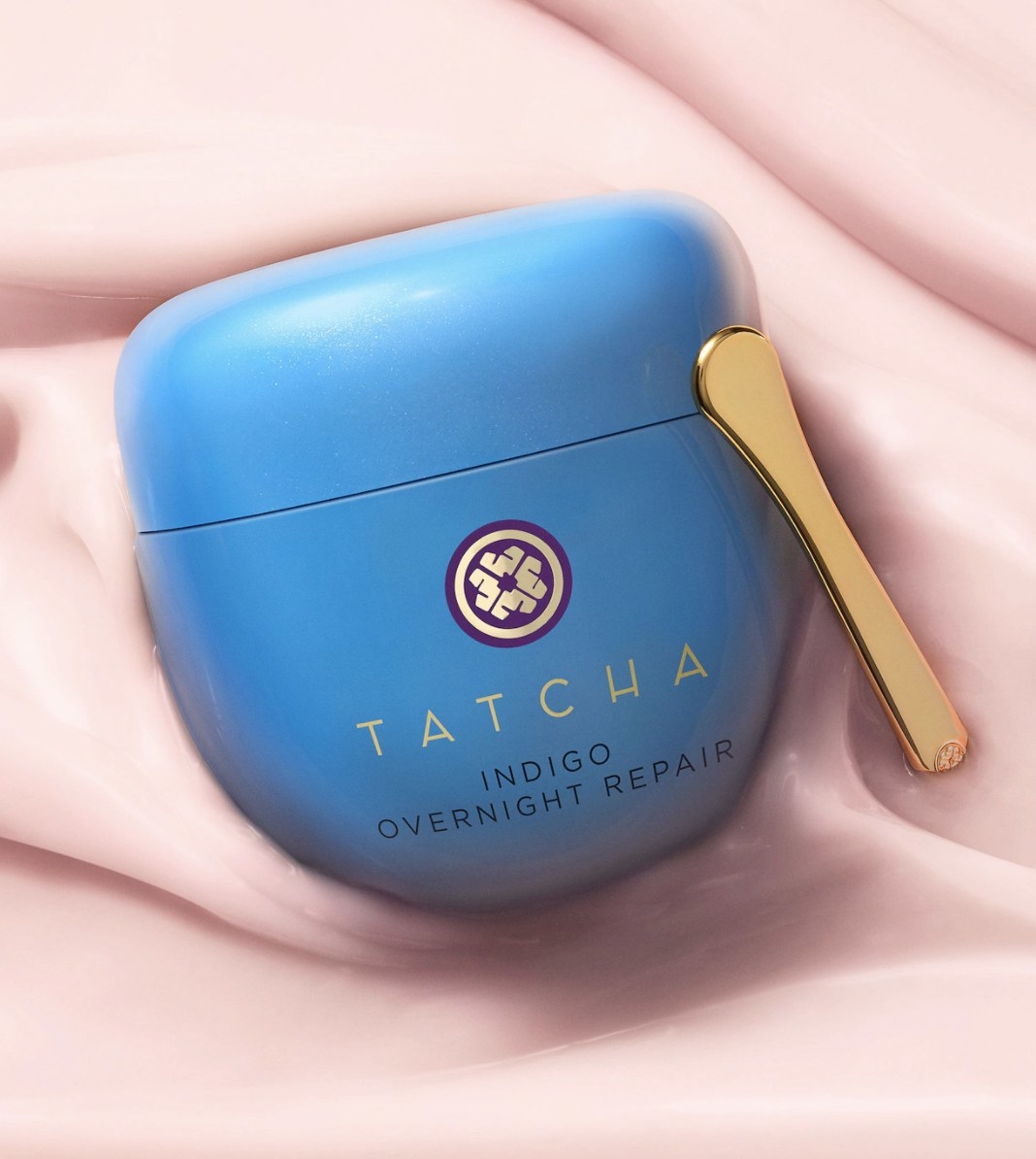 The blue container has a purple and gold emblem and says &quot;TATCHA INDIGO OVERNIGHT REPAIR&quot; and has a small gold spatula