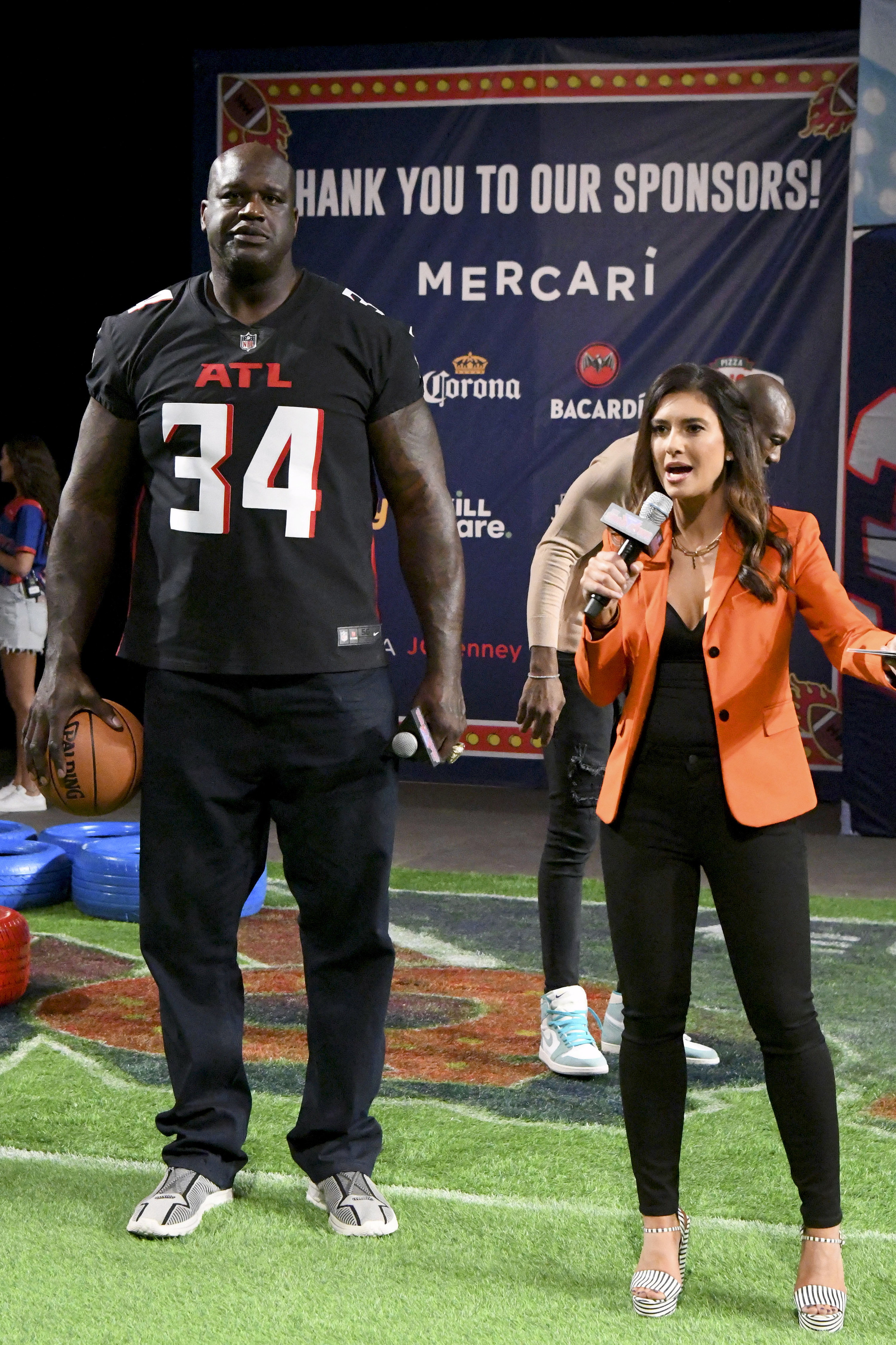 Shaq next to a host on a football field