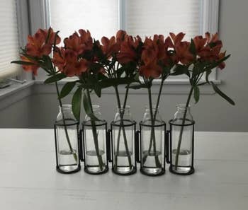 A reviewer photo of a five piece vase set with orange flowers