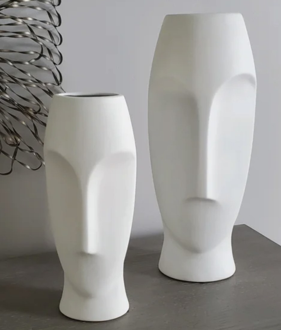 A reviewer photo of two white face vases