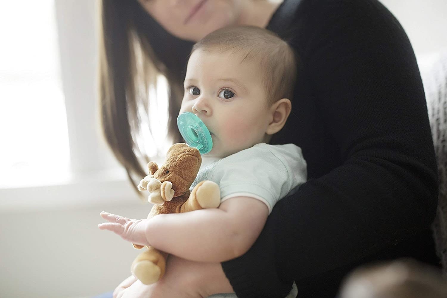 a baby with a moose plush attached to a pacifier