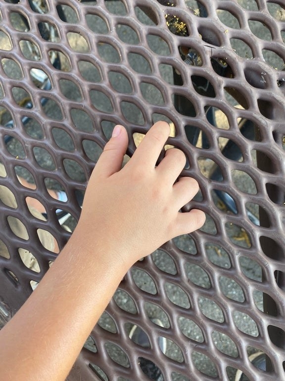 fingers stuck through a woven table