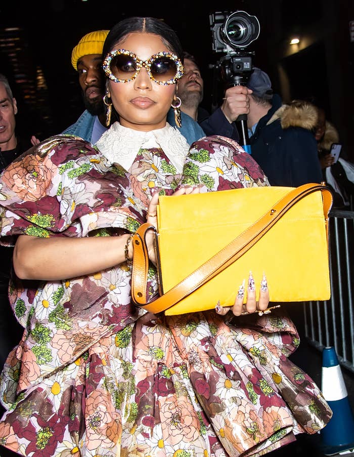 Nicki Minaj carries a purse as she walks down the street in a floral print dress and large sunglasses