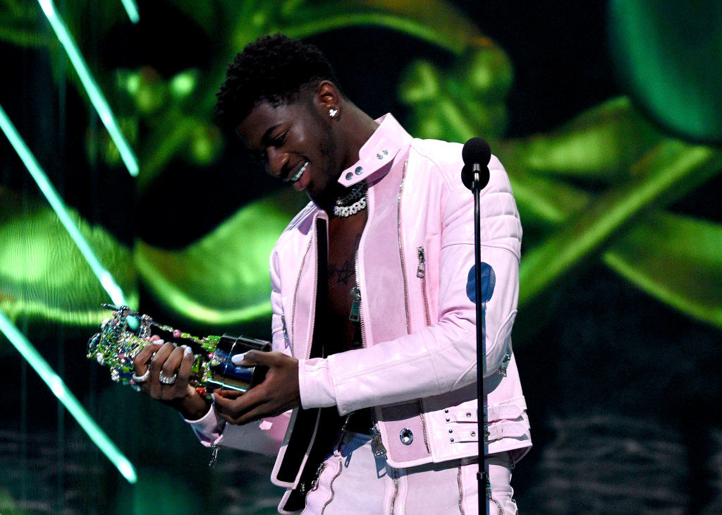 Lil Nas X looking at his award on stage