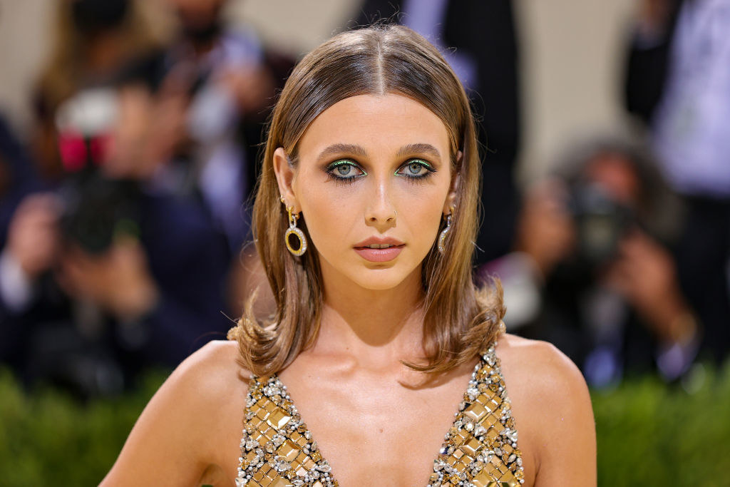 A close up of Emma Chamberlain shows her colorful eyeshadow and dangling earrings