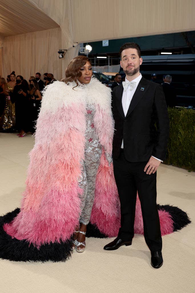 Serena Williams wears a lace glittery body suit under a floor length fuzzy three-toned cape and Alexis Ohanian wears dark suit