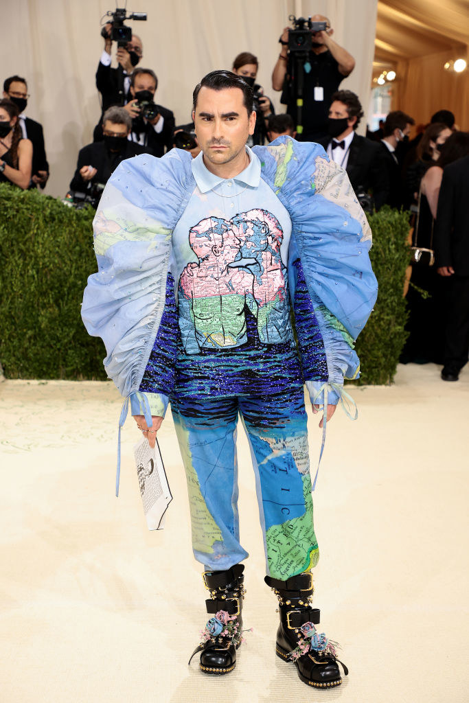 Dan Levy attends The 2021 Met Gala in a printed shirt/pant combo that features two people kissing and a map of the world