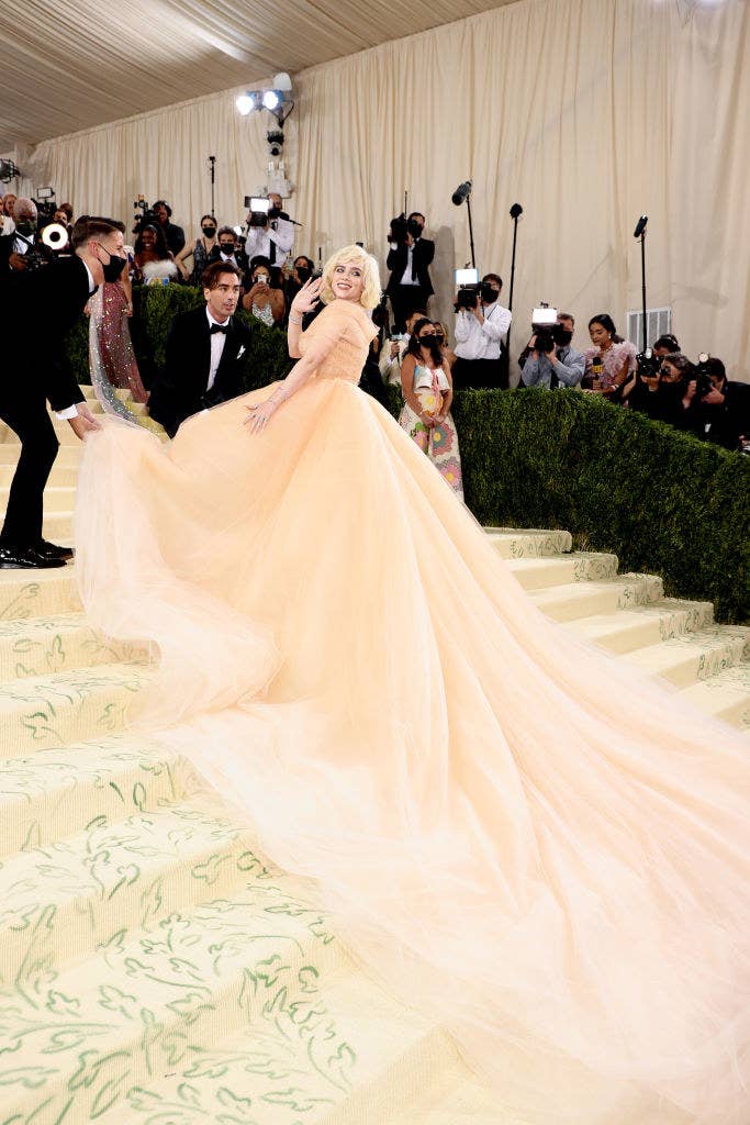 Billie stands on the steps of the Met Gala in a ball gown with an off-shoulder neckline and Marilyn Monroe-inspired hair