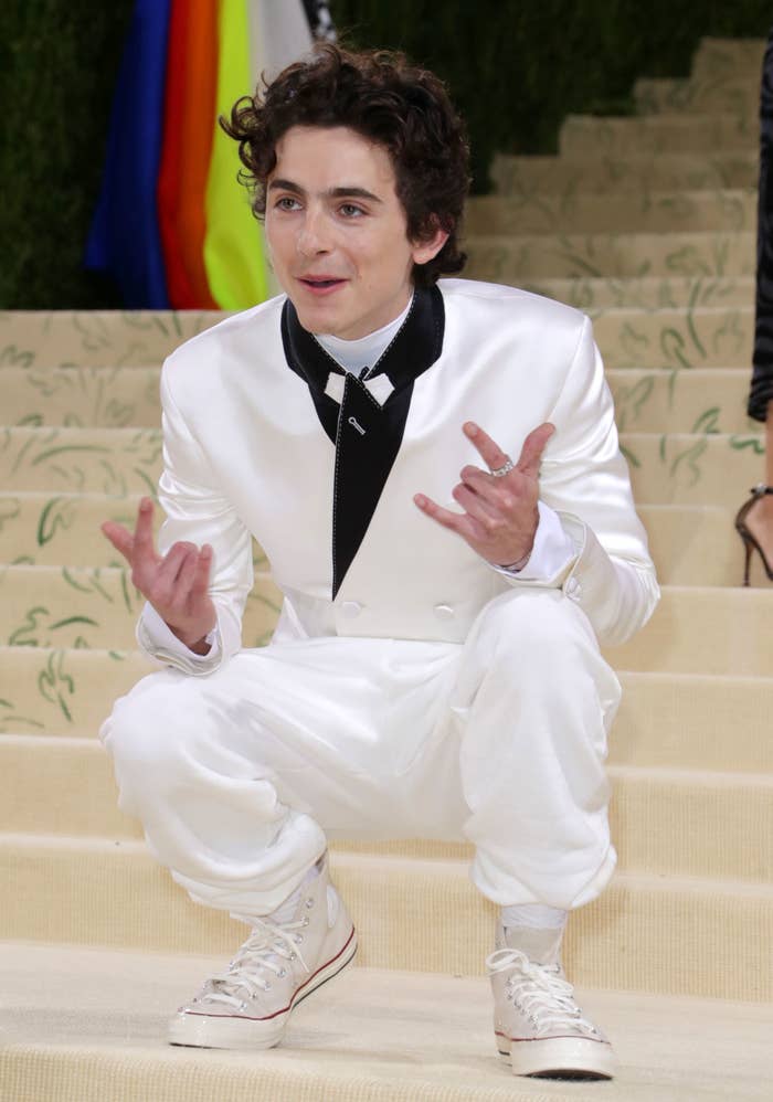 Timothée crouching down on the Met Gala steps as he poses for the paparazzi