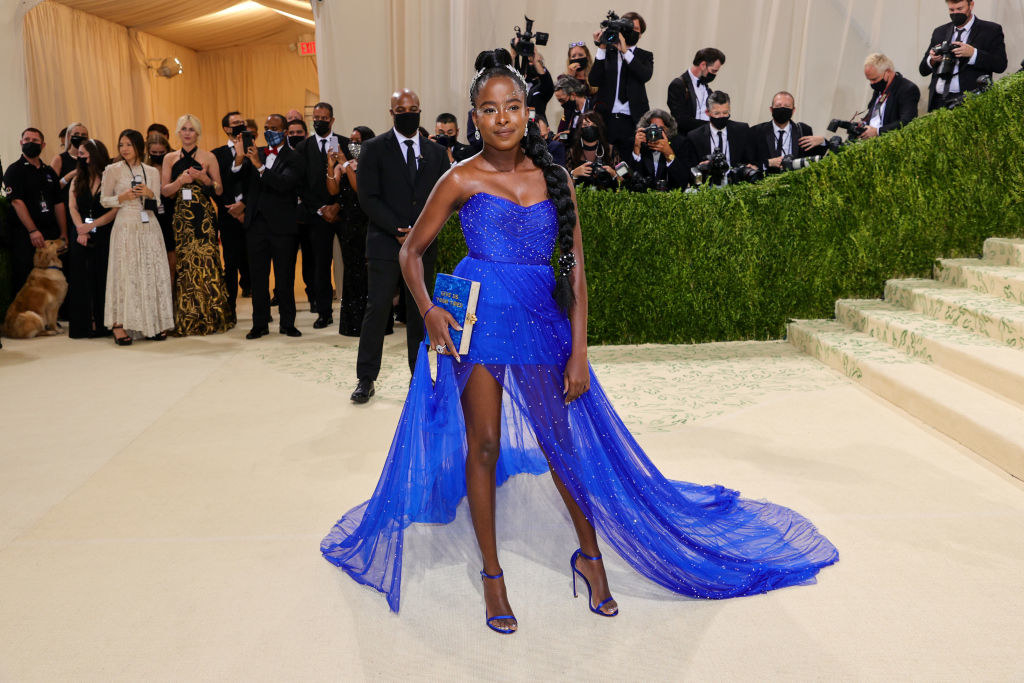 Amanda Gorman wears a short brightly colored dress with a long train