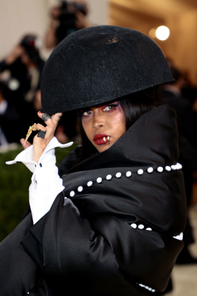 A close up of Erykah Badu as she poses while looking over her shoulder