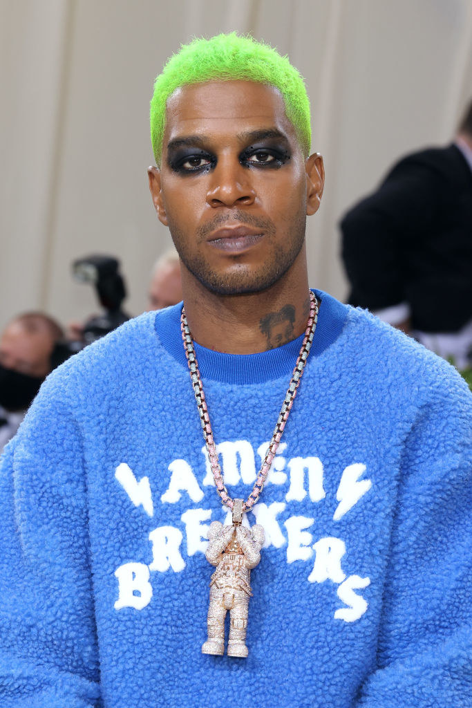 A close up of Kid Cudi as he shows off his dark eye makeup and neon colored hair
