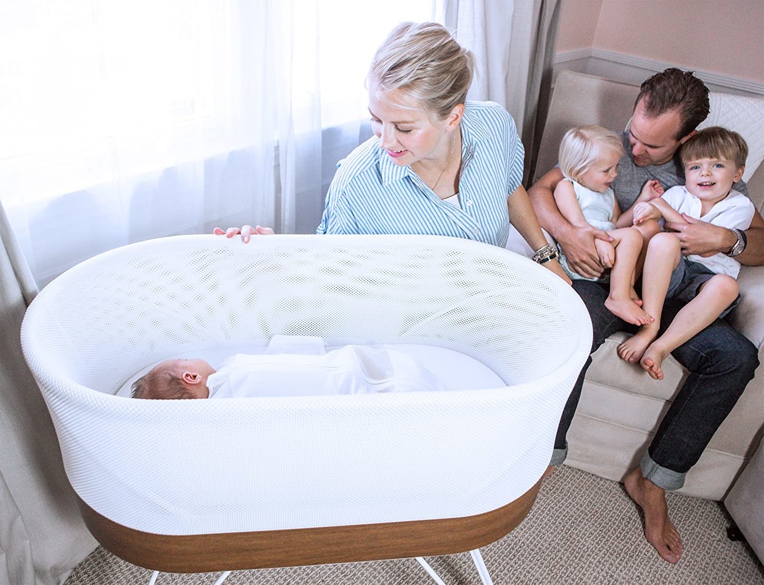 a family looking in on the baby in the white snoo bassinet with walnut accents