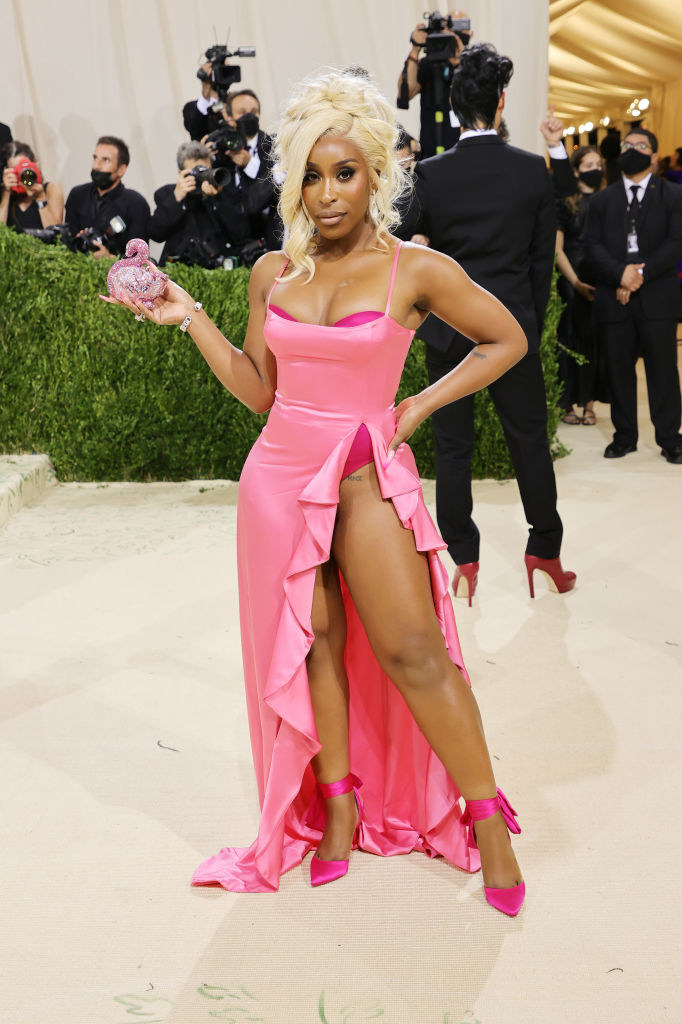Jackie Aina poses on the Met Gala red carpet with her hand on her hip