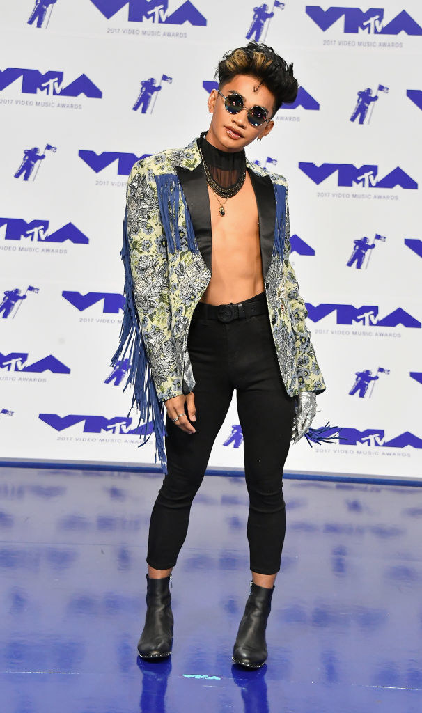 open paisley jacket with fringe on sleeve, no shirt, tight pants