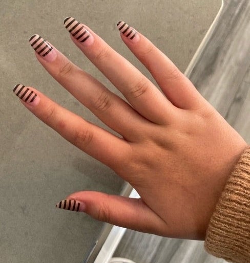 A hand with nails that are painted with stripes