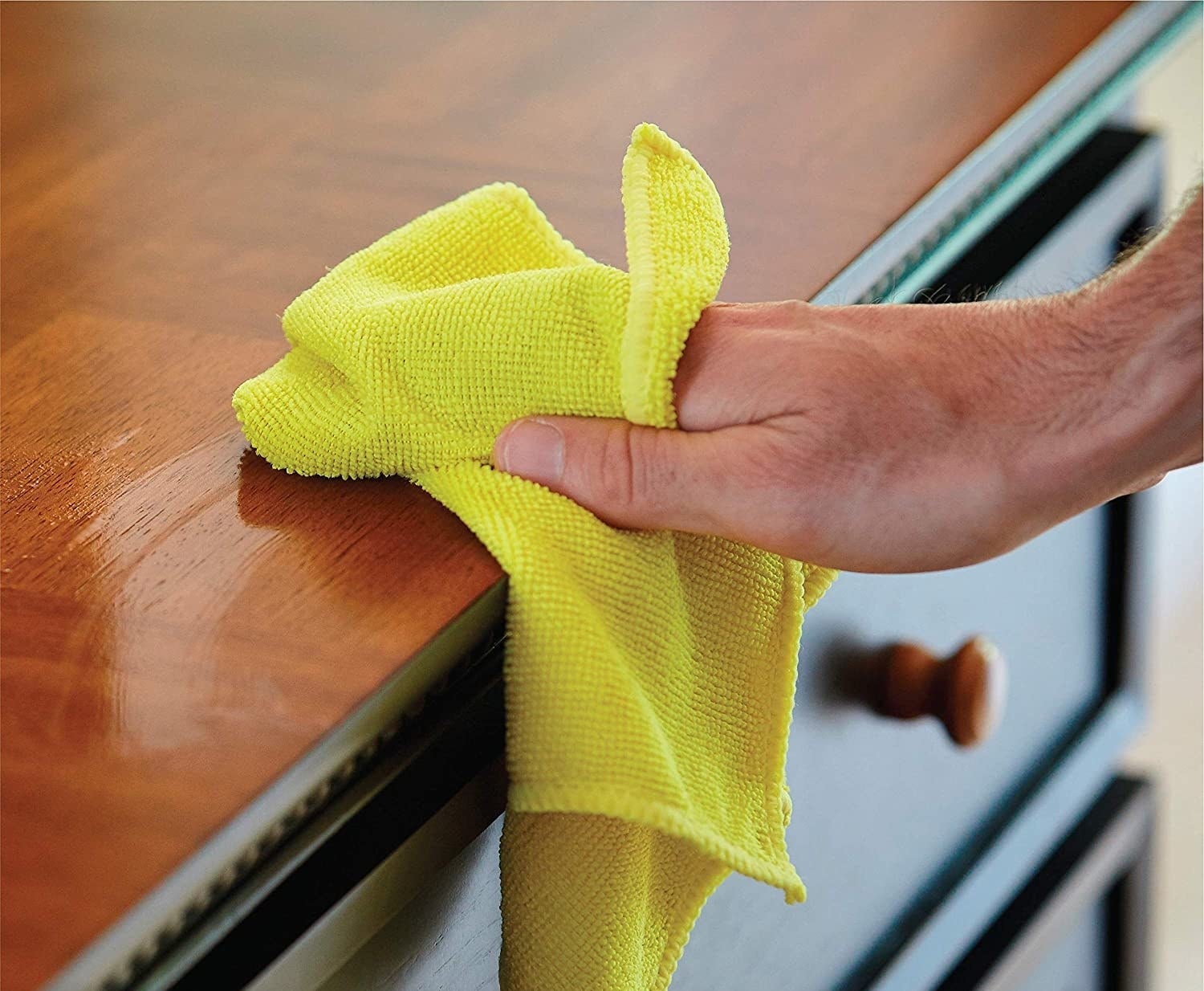 A person wiping a counter with a thick cloth