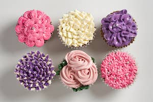 a bunch of flower frosted cupcakes
