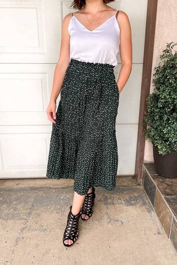a reviewer wearing the skirt in forest green with a satin white camisole 