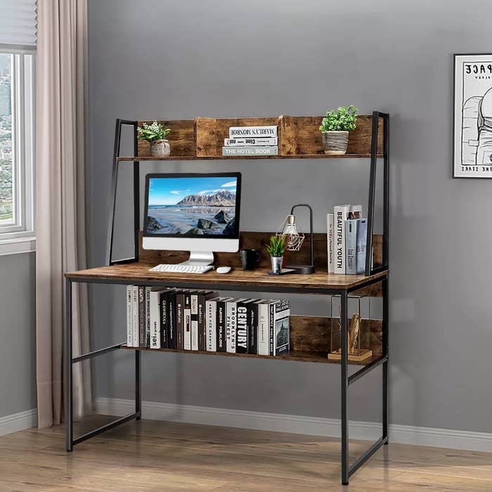 Rustic wooden desk with bookcase on bottom shelf, cube storage on upper shelf with decor, computer on main desk